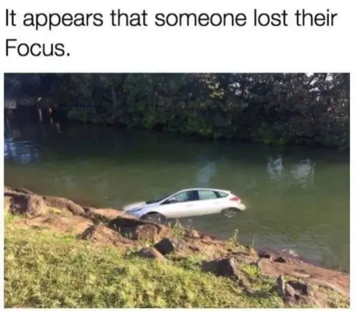 A white Ford Focus car barely floating above water level with caption above the picture "It appears that someone lost their Focus"